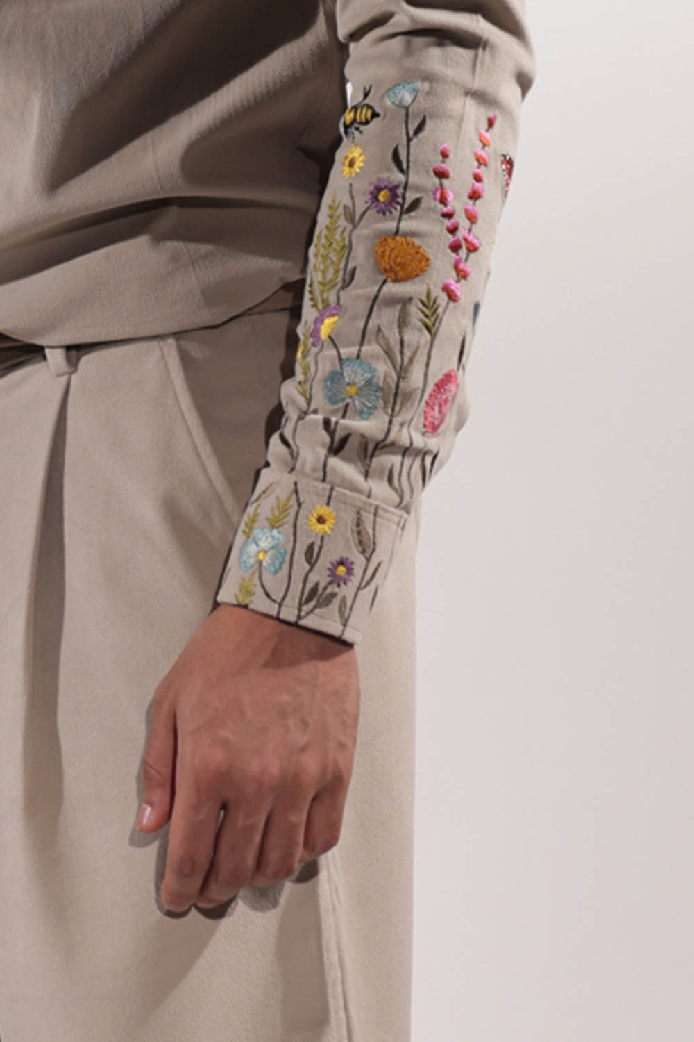 Beige suede shacket with mountain-inspired pockets and floral embroidery